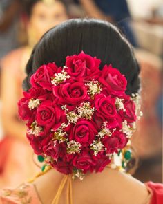 a woman with a bunch of red roses in her hair is wearing a bridal hairstyle