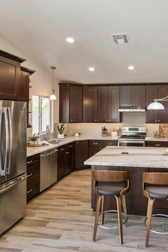 a large kitchen with wooden cabinets and stainless steel appliances, along with two bar stools