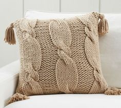 a white couch with a knitted pillow on it