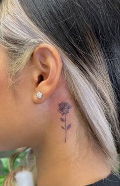 a woman with a small tattoo on her left side behind her ear and behind her ear is a single rose