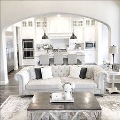 a living room filled with white furniture and lots of pillows on top of a rug