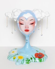 a ceramic figurine with flowers on it's head and clouds above her head