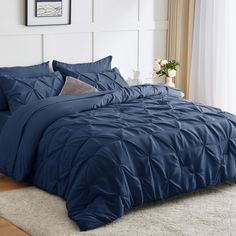 a bed with blue comforter and pillows in a room next to a white wall