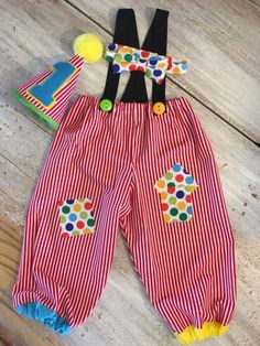 a pair of red and white striped shorts with polka dots on the bottom, black suspenders, and yellow pom - poms