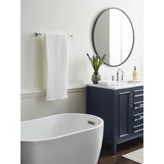 a white bath tub sitting next to a bathroom sink under a round mirror on a wall