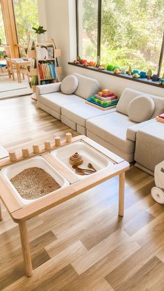 a living room filled with lots of furniture next to a wooden floor covered in toys