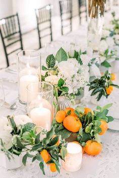 the table is set with candles, flowers and oranges for an elegant wedding reception