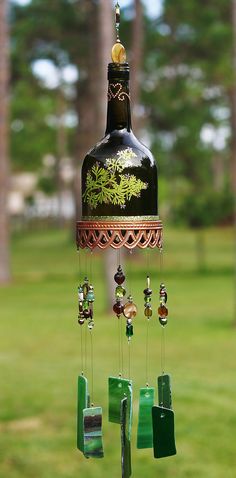 a wind chime hanging from the side of a green grass covered field with trees in the background