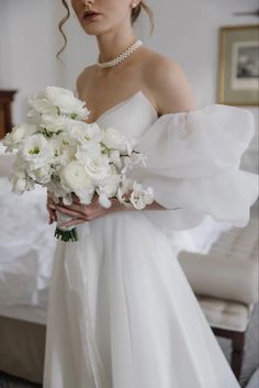 a woman in a white dress holding a bouquet of flowers