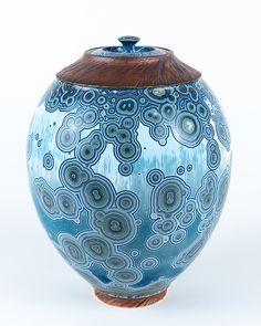 a blue and brown vase sitting on top of a white table