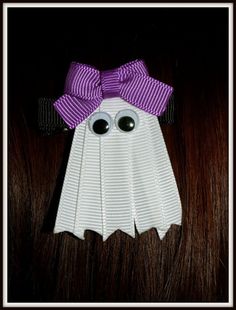 a close up of a paper ghost with eyes and a purple bow on it's head