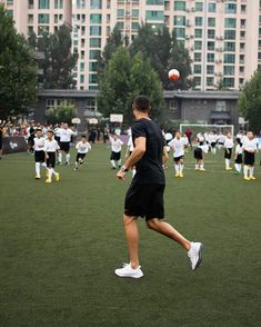 a group of people on a field playing frisbee with buildings in the background