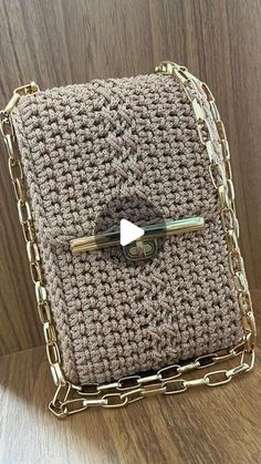 a crocheted purse with a gold chain around the clasp and a bow on it