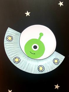 a paper plate with a green alien on it's face and stars around it