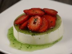 there is a small white plate with some food on it that has green sauce and strawberries