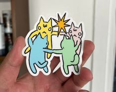 a person holding up a sticker with three cats on it's back and one star above the other