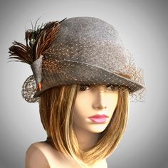 This beautiful ladies cloche is made from fur felt, and hand draped over an antique hat block, and embellished with french veiling, and feathers, which may vary depending on availability.     Please indicate your head size measurement when ordering (measure your head horizontally just above your eyebrows). When you receive your hat, there will be a small ribbon inside to fine-tune the fit, and a hat box for safe storage. Note: Colors will vary depending on your monitor and there will also be some variations due to dye lots. I personally create each hat one at a time, and no two are ever exactly the same.  My hats are 100% handmade for you, using traditional Millinery techniques and the highest quality fabrics and details.  I frequently trim  my hats with one-of-a-kind details, i.e. vintage Elegant Gray Felt Hat With Short Brim, Elegant Gray Brimmed Felt Hat, Evening Fascinator With Feather Trim And Short Brim, Evening Mini Hat With Feathers And Short Brim, Elegant Feathered Fedora Felt Hat, Elegant Fedora Felt Hat With Feathers, Gatsby Style Cloche Hat For Kentucky Derby, Elegant Feathered Hat For Winter, Elegant Fedora With Feather Trim