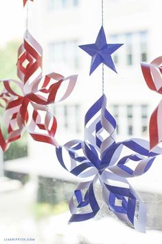 red, white and blue paper stars hanging from a string in front of a window