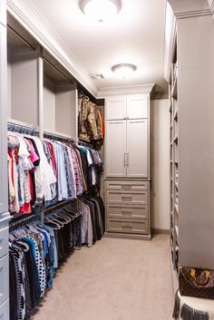 a walk in closet with lots of clothes hanging on the wall and drawers below it