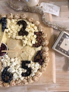 Clock themed snack board with number 1-6 on a wooden board with black and white snack foods. Themed Charcuterie Board, Fun Halloween Snacks, Cheddar Cheese Ball, Brunch Tablescape, Cream Cheese Ball, Holiday Cheese, Christmas Cheese, Snack Board, Cheese Ball Recipes