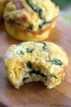 an egg muffin with spinach and ham is cut in half on a cutting board