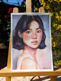 a portrait of a woman is displayed on an easel with flowers in the background