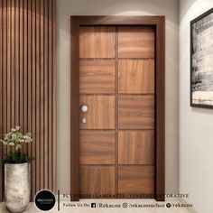 a large wooden door sitting in the middle of a room next to a vase with flowers