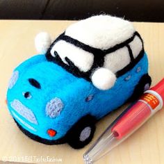 a blue toy car sitting on top of a wooden table next to a marker and pen