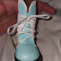 a hand holding a blue and white shoe with laces on it's side