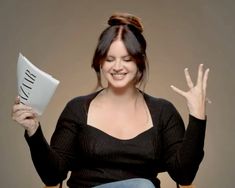 a woman sitting in a chair holding up a white object with the word i love you written on it