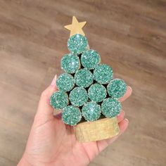 a hand holding a green christmas tree made out of gummy balls with a gold star on top