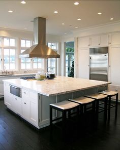 a large kitchen with an island, stove and oven in the center is surrounded by white cabinets