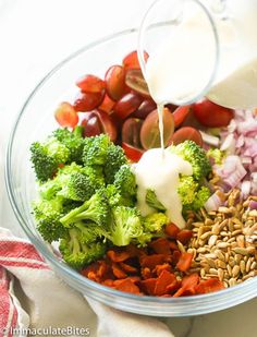 broccoli, tomatoes, onions, sunflower seeds and milk being poured into a bowl