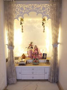 an image of a doll sitting on a table in front of a window with curtains