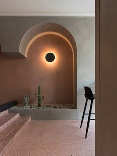 the interior of a house with an arch and cactus in the foreground, along with stairs leading up to it