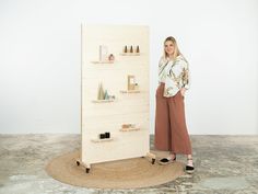 a woman standing in front of a shelf with bottles on it