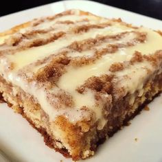 a close up of a piece of cake on a plate with white icing and cinnamon crumbs