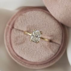 an engagement ring sitting on top of a pink velvet box with a diamond in it