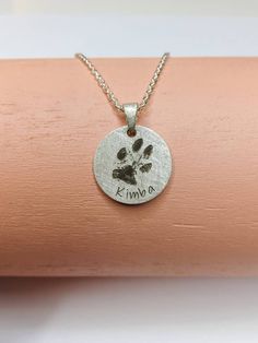 a small dog paw print on a silver disc with the word kma in it's center