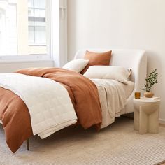 a bed with two pillows on it in a room next to a window and side table