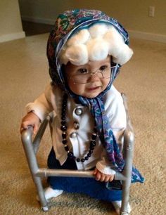 a baby sitting on top of a metal chair wearing a hat and eyeglasses