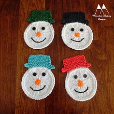 three snowmen made out of crochet sitting on top of a wooden table