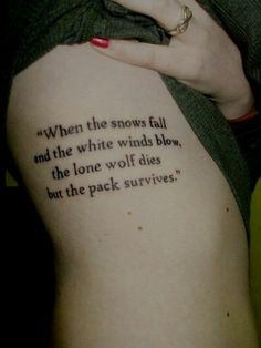 a woman with a tattoo saying when the snows fall and the white winds blow, the lone wolf dies but the pack survive