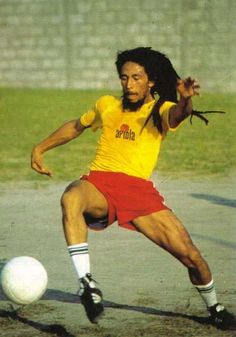 a man kicking a soccer ball on top of a field