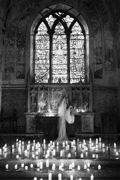 a bride and groom standing in front of many lit candles at their wedding ceremony on the altar