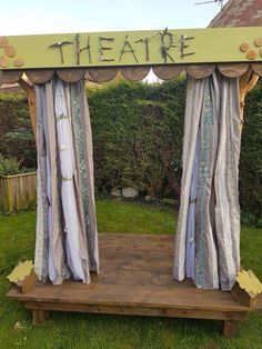 an outdoor stage with curtains and writing on the top that says theatre in front of it