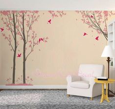 a living room with a white chair next to a tree and birds painted on the wall