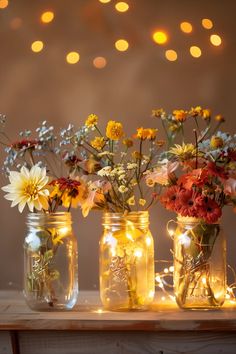 three mason jars filled with flowers and lights