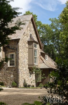 a stone house surrounded by trees and bushes