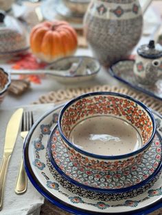 a table set with plates, silverware and pumpkins